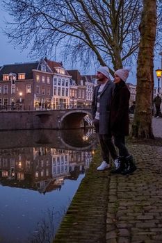 couple on a city trip in Utrecht, mid age Asian woman and European men visit Utrecht, Traditional houses on traditional houses on the Oudegracht Old Canal in the center of Utrecht, Netherlands Holland Europe