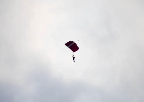 silhouette parachute stunt unfocused and blurry while gliding in the air with blue sky