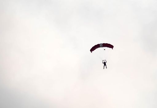 silhouette parachute stunt unfocused and blurry while gliding in the air with blue sky