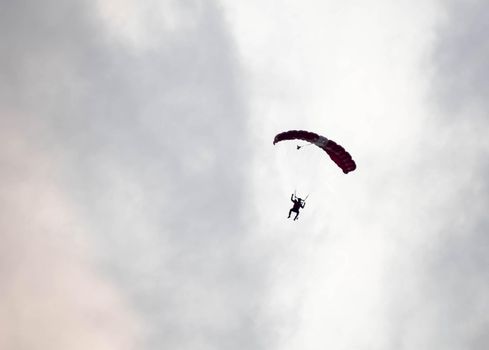 silhouette parachute stunt unfocused and blurry while gliding in the air with red smoke trail during an air exhibition in Singapore