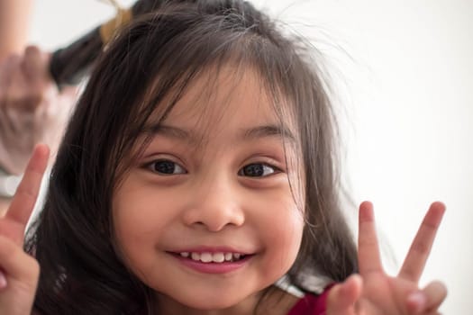 Stylist curling hair for little girl in a parlor. Pretty little girl with curly hair and make up