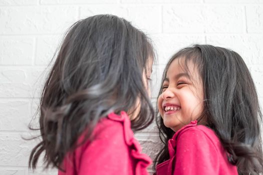 Pretty little girl twins having fun and kissing each other on White background