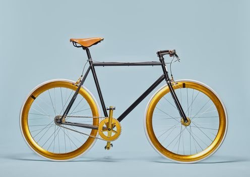 Trendy black an gold bicycle isolated on a blue background