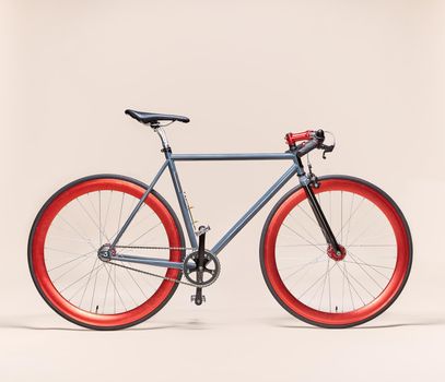 Trendy blue and red bicycle isolated on a pale pink background