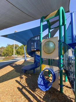 Children playground activities in public park. Slide, swing on modern playground. Urban neighborhood childhood concept. 