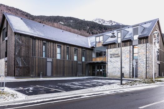 Saint Lary Soulan, France - December 26, 2020: architectural detail of the Maison de Sante (health house) in the historic city center where tourists walk on a winter evening