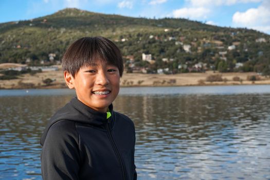 Portrait of young sporty Asian boy by the Lake. Teenager concept