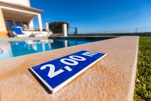 blue plastic plate at the edge of a swimming pool indicating a depth of 2.00 meters