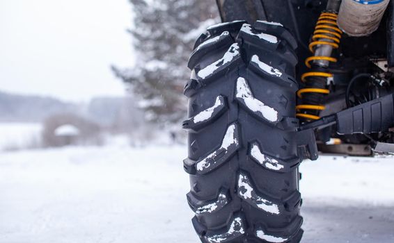 Close-up of a quad bike wheel and 4-wheel drive. ATV in the forest in winter. Riding a quad bike.