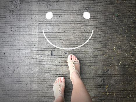 Smile face on road and woman feet background