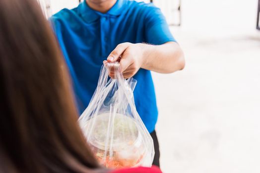 Asian young delivery man in blue uniform he making grocery service giving rice food boxes plastic bags to woman customer receiving front house under pandemic coronavirus, Back to new normal concept