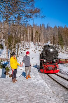 couple men and woman hiking in the Harz national park Germany, Steam train on the way to Brocken through the winter landscape, Famous steam train through the winter mountain. Brocken, Harz Germany
