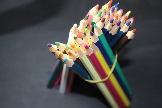 Close-up view of bright colored multicolor pencils on black background