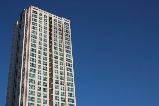 The wide-angle view of a skyscraper commercial building with blue sky on sunny day.