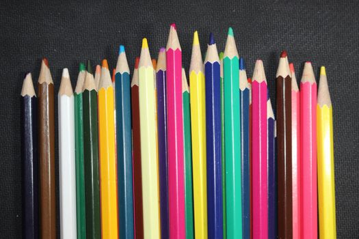 Close-up view of bright colored multicolor pencils on black background