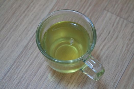 Glass cup having brewed fragrant green tea or qehwa or qahwa on the wooden floor. It is served with sugar or honey and nuts