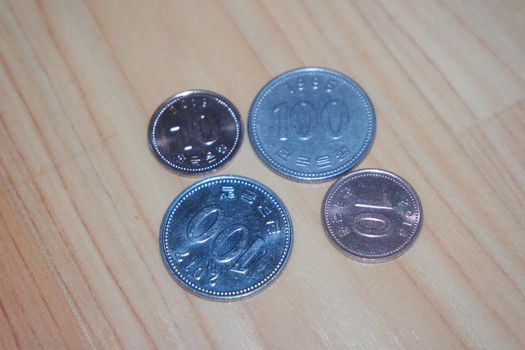 Silver shining Korean won coin scattered over a wooden floor.