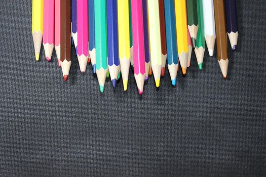 Close-up view of bright colored multicolor pencils on black background