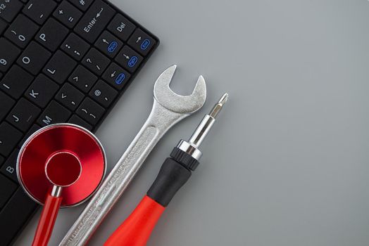 Computer repair or maintenance concept with a stethoscope to check the status or health of the device on top of a laptop with screwdriver and spanner