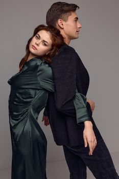 The woman leaned on the back of the man on a gray background side view. High quality photo
