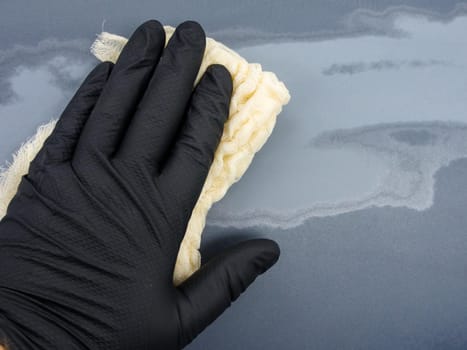 the hand of the auto-painter in a black glove holds a special napkin for dusting the surface of the car. preparation for painting the car
