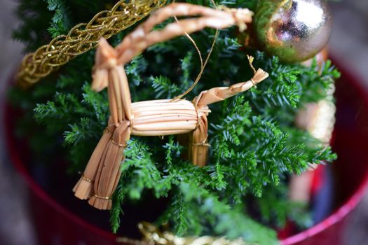 Close up of a straw horse at a small decorated christmas tree
