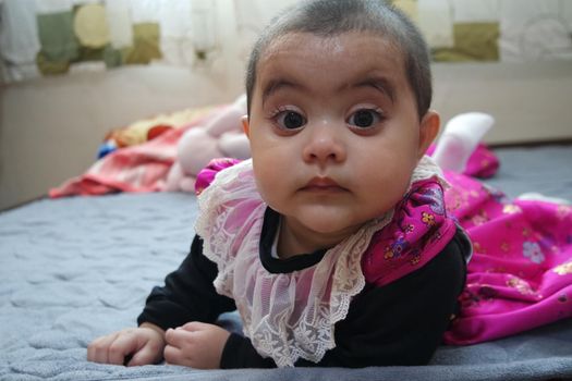 Baby girl with lovely face, big eyes and cute face gesture. Toddler baby making sweet activities