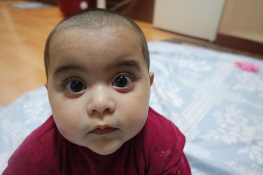 Baby girl with lovely face, big eyes and cute face gesture. Toddler baby making sweet activities