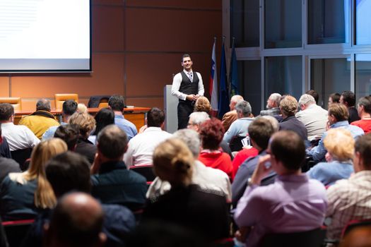 Speaker giving a talk in conference hall at business meeting event. Rear view of unrecognizable people in audience at the conference hall. Business and entrepreneurship concept.