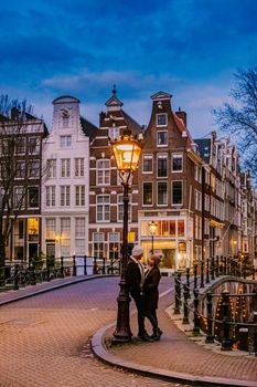 Amsterdam Netherlands during sunset, historical canals during sunset hours. Dutch historical canals in Amsterdam, couple on city trip in Amsterdam , men and woman during evening by the canals