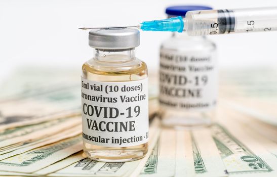 Covid-19 coronavirus vaccine with hypodermic syringe needle sitting on pile of cash to suggest payment for early vaccination