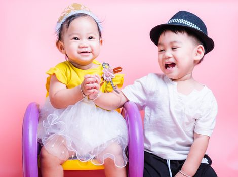 Asian Little brother and her baby girl in beautiful dress sitting on chair,  Family with children in studio on pink background