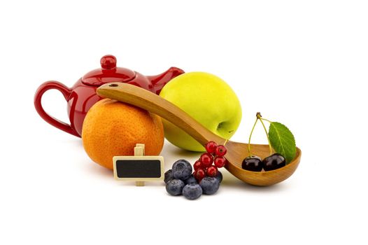 Fresh seasonal fruit still life with assorted berries including blueberries, cherries and red currants on wooden spoons with apple and orange and colorful red teapot