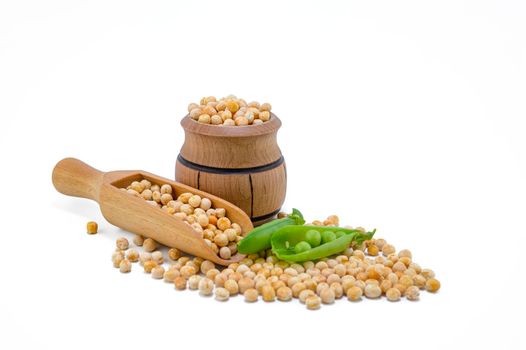 Dried peas spilling from a wooden barrel, wooden scoop and fresh plant with pods isolated on a white background