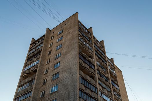 typical mid-russian silicate brick high rise condominium residential building, upward view on blue sky background