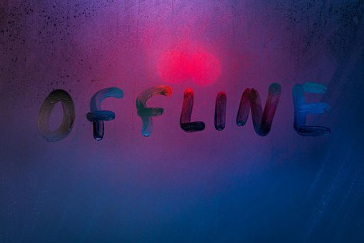 the word offline handwrittern on foggy glass with cold neon blue back light
