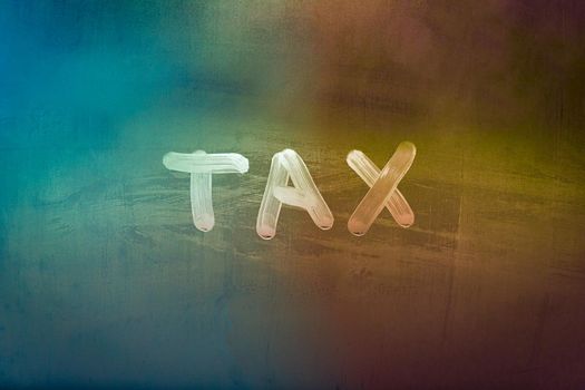 word tax hadwritten on night wet window glass surface with green and orange colors in blurry background