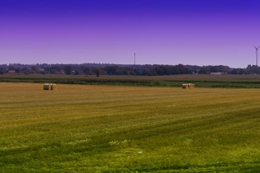 Straw bales on farmland with blue cloudy sky 