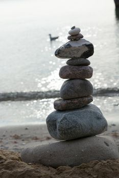 Stones stacked on top of each other on the beach with sea view in the background