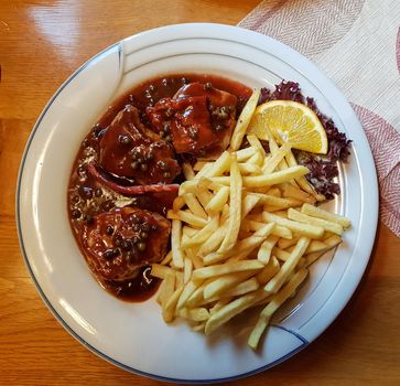 Various grilled meats with french fries on white dish