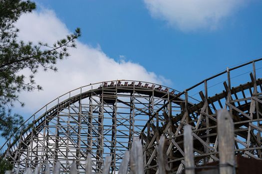 Unrecognizable persons on a roller coaster in an amusement park.