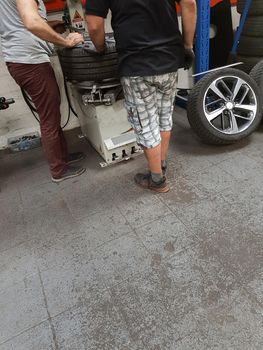 Engineer assembles car wheel on balancer in the workshop