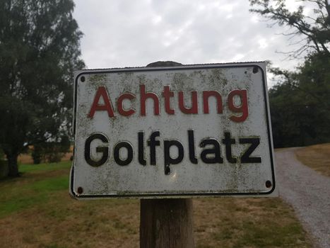 Rectangular sign with inscription in German Caution golf course