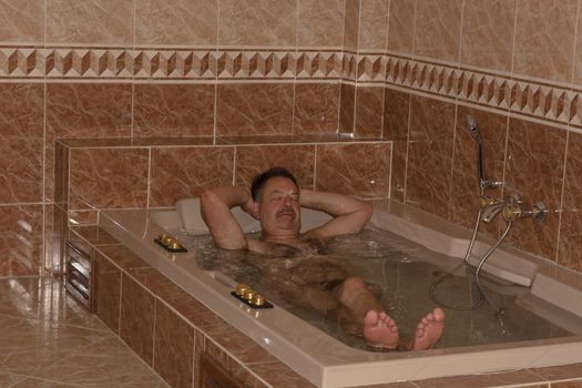 Man in luxury bathroom with whirlpool, shower and sink