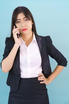 Young Asian women in suit standing posing using her phone against blue background