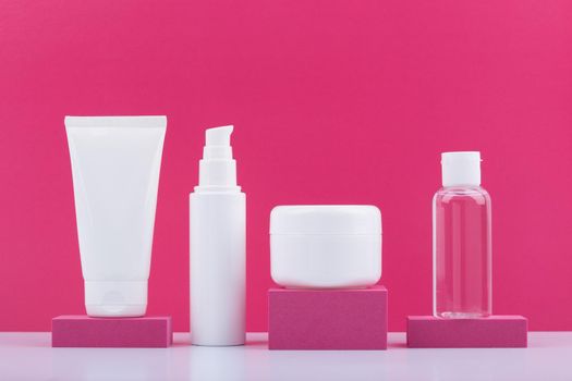 Still life with set of cosmetic products on pink podiums against bright pink background. Concept of beauty routine and skincare. High quality photo