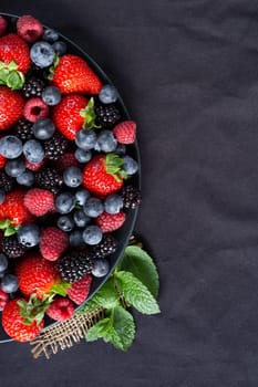 Strawberries, blackberries, rasberries, green mint on canvas black bakground. Mock up, menu, cafe poster concept