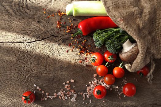 Diferent vegetables in canvas bag on wooden bakground. Ructic style of kitchen