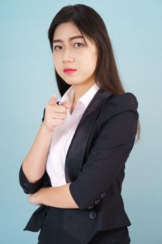 Asian woman looking at camera and pointing finger on blue background