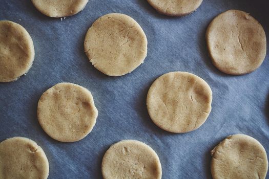 Round pieces of shortbread dough for making cookies or gingerbread are on paper. Homemade baking with your own hands. Top view